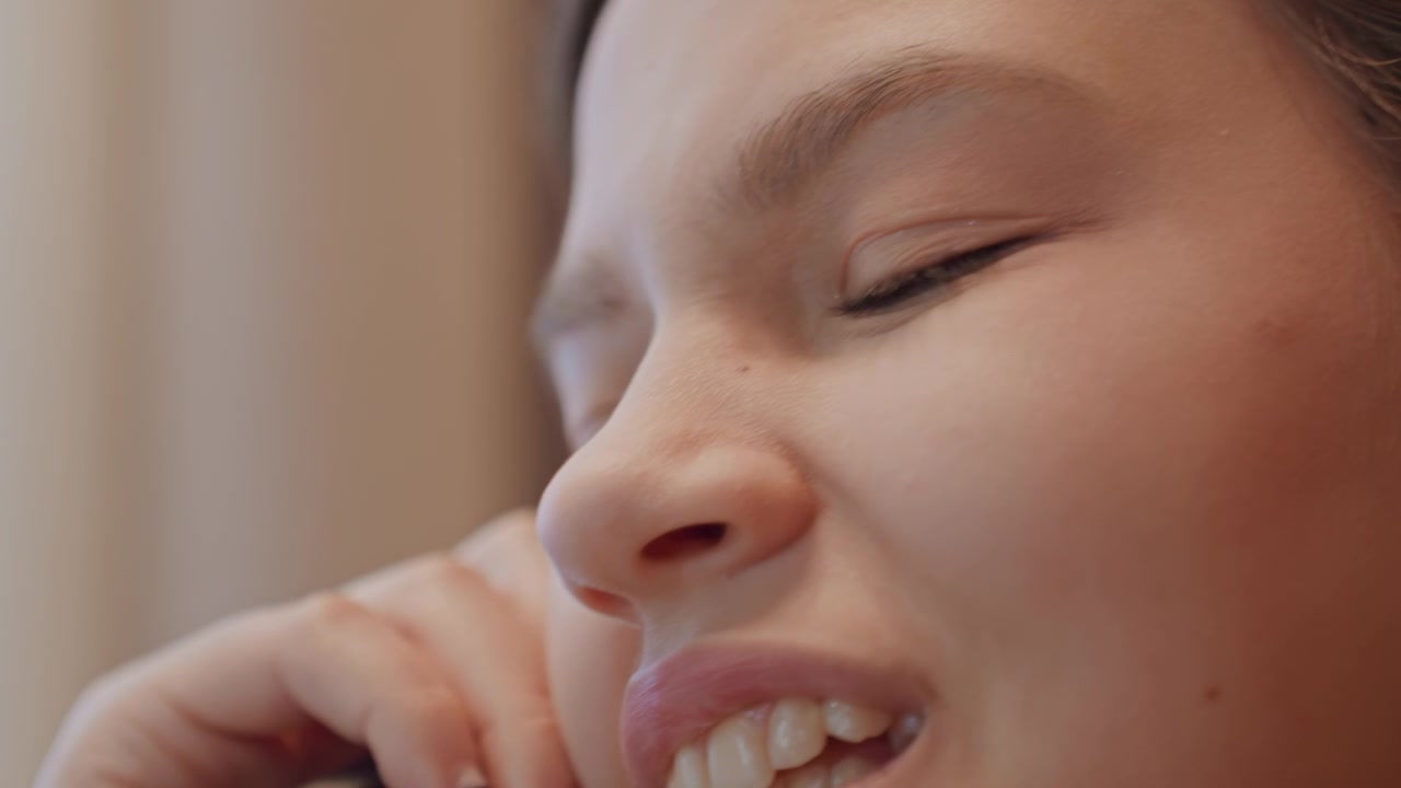 Closeup phone listening eyes and profile capture contemplative mood teenage student on break daydreaming between sentences, soft eyelids and tiny smile, warm window light, natural makeup, relaxed
