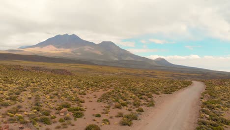 Aerial-cinematic-shot-revealing-a-beautiful-scenery-following-a-dirt-road-in-the-Atacama-Desert,-Chile,-South-America