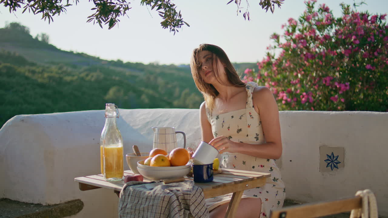 자연을 바라보는 테라스에서 즐기는 머리카락을 흔들고 휴식을 취하는 여성. 점심을 준비하는 여성