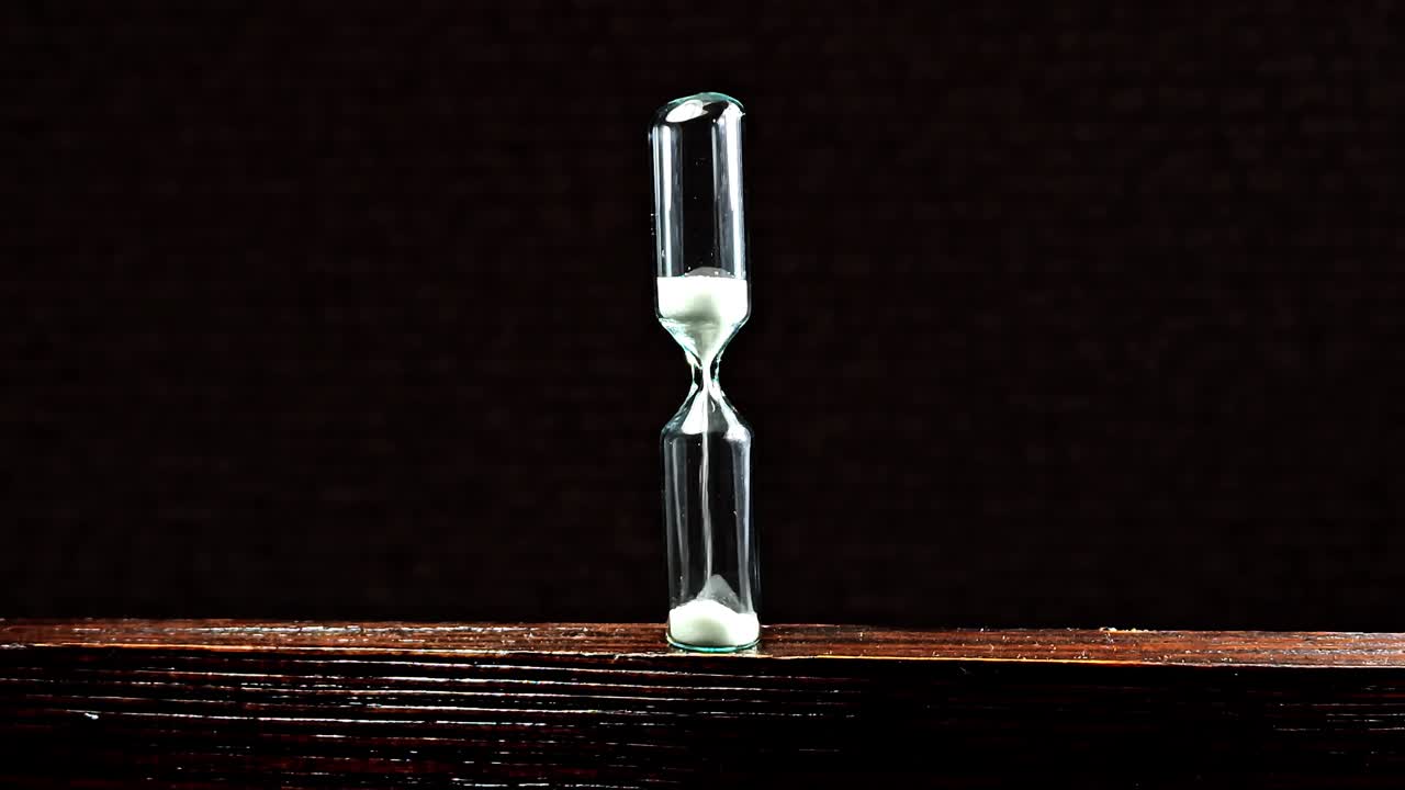 Sand clock on wooden background. Hourglass as time passing concept.