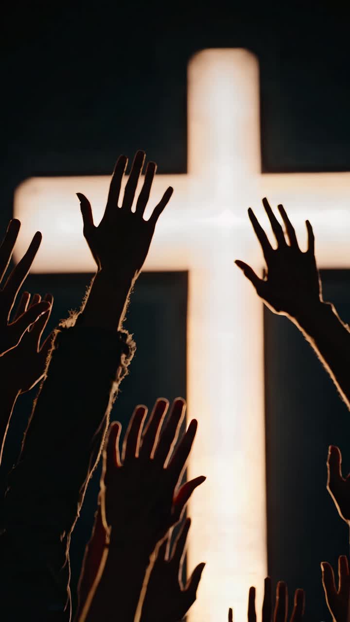 Silhouetted hands reaching towards a glowing cross, captured from a low angle