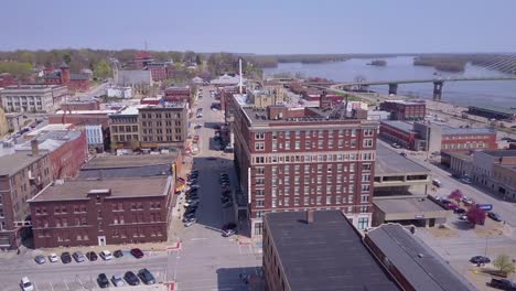 Toma-Aérea-Ascendente-Sobre-La-Pequeña-Ciudad-De-América-Burlington-Iowa-Downtown-Con-El-Río-Mississippi-Antecedentes-1