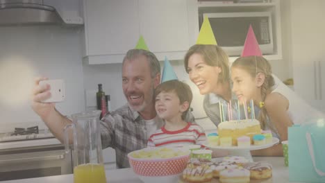 video compuesto de puntos de luz contra caucásicos tomando una selfie durante una fiesta de cumpleaños