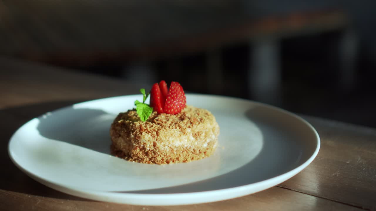 un pequeño pastel de napoleón con fresas en la parte superior de pie en un plato blanco