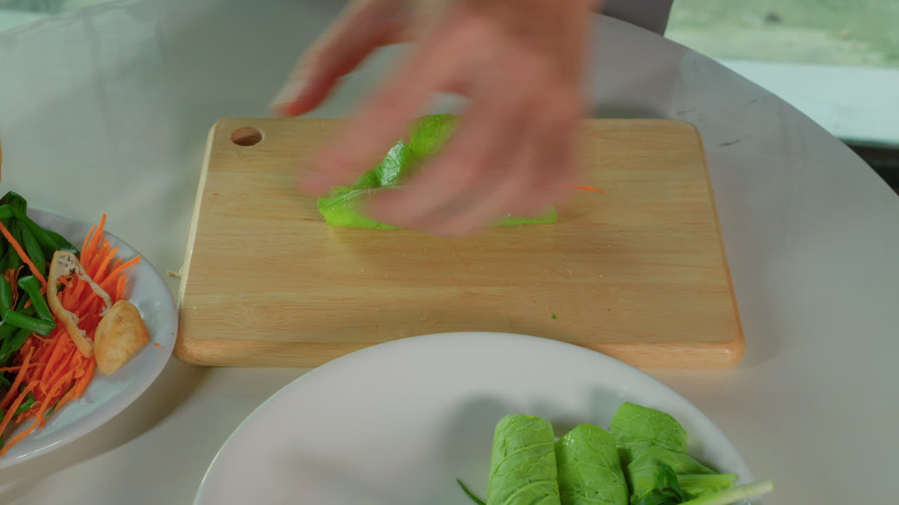 chef hand close up rolling a salad leaf with vegetable inside preparation recipe of spring roll traditional Vietnamese food dish