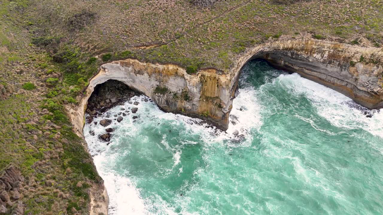Drone footage captures rugged cliffs and turquoise waves along Port Campbell's coastline in natural light