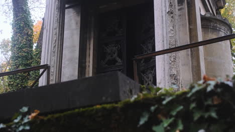 Tiro-Ascendente-De-La-Entrada-De-Una-Misteriosa-Bóveda-Familiar-En-El-Cementerio-Pere-Lachaise-La-Puerta-De-Metal-Está-Entreabierta