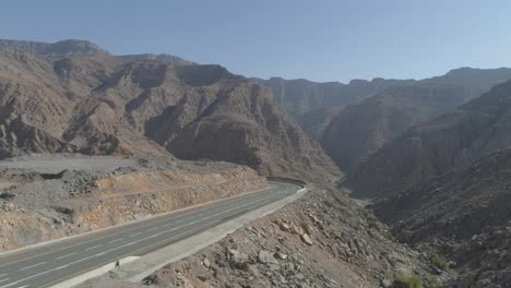 Cineamtic-drone-sliding-shot-of-a-road-with-a-rocky-mountain