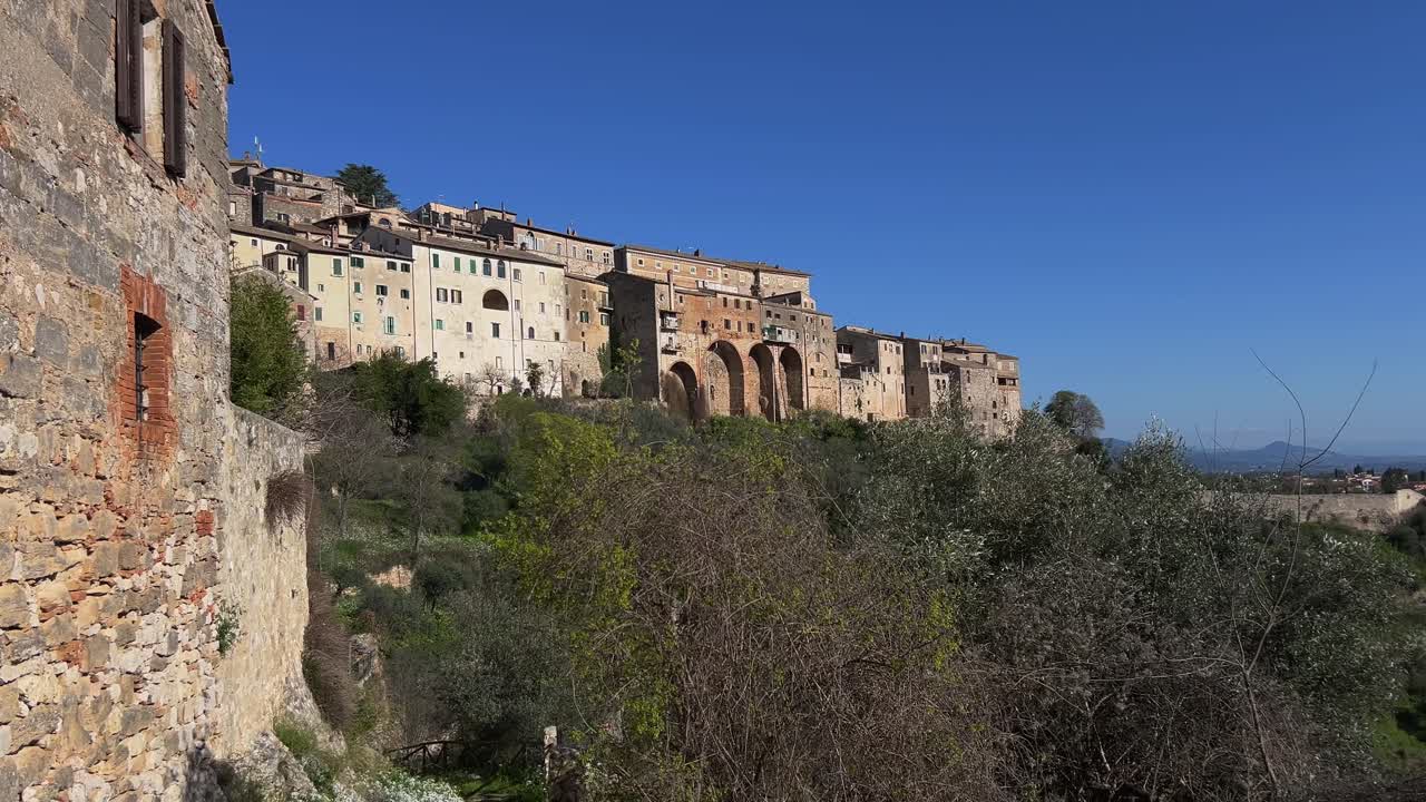 Panning shot revealing the massive, ancient cyclopean walls and historic buildings of the hilltop town of Amelia in Umbria, Italy, on a clear day