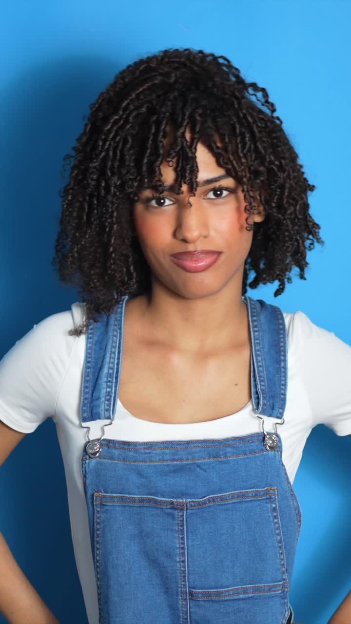 Woman Making Heart Shape with Hands in Overalls