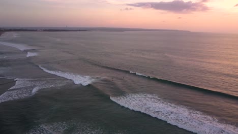 Drone-video-of-surfers-riding-waves-at-Canggu-Beach-in-Bali,-Indonesia