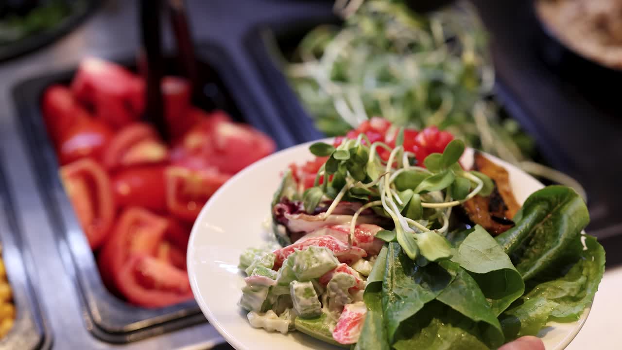 Hand adds microgreens to colorful salad plate at well-lit, self-serve vegetable buffet station