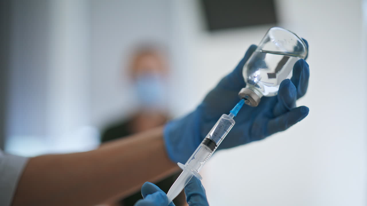 Medical nurse hands preparing vaccine injection closeup. Doctor filling syringe