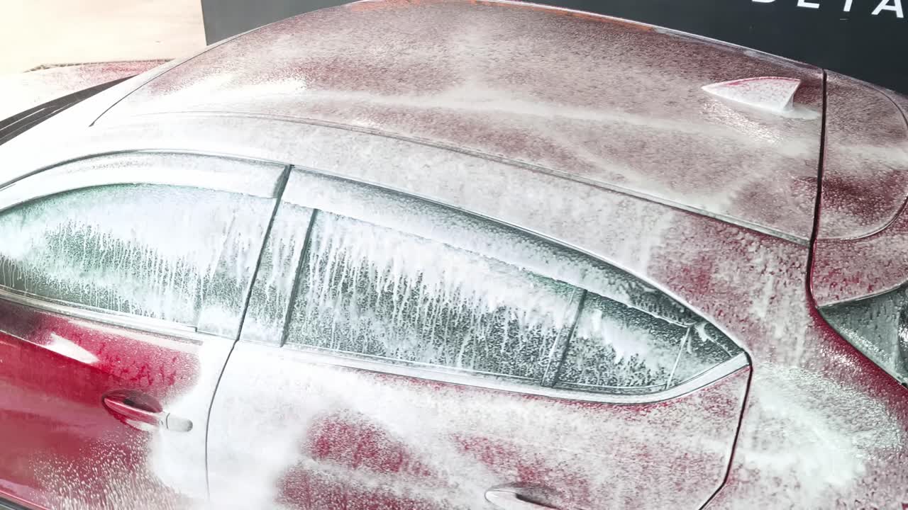 Red Car Covered in Foam During Car Wash