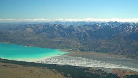 紐西蘭南島特卡波湖 (lake tekapo) 上的河流景觀飛行,背景是南阿爾卑斯山和岩石山脈