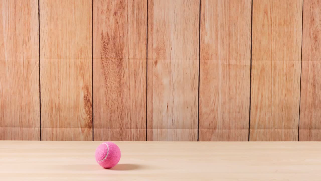 A pink tennis ball moves across a shelf