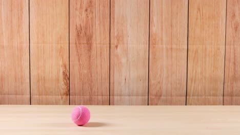 una pelota de tenis rosa se mueve a través de un estante