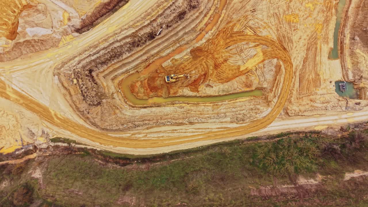 Sand quarry under development with machinery in action during daytime