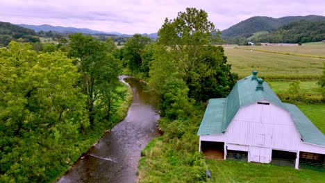 aerial push over treetops to farm scene and barn near mountain city tennessee