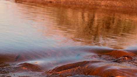 running stream water glistens over rocks with sunlight reflections on top