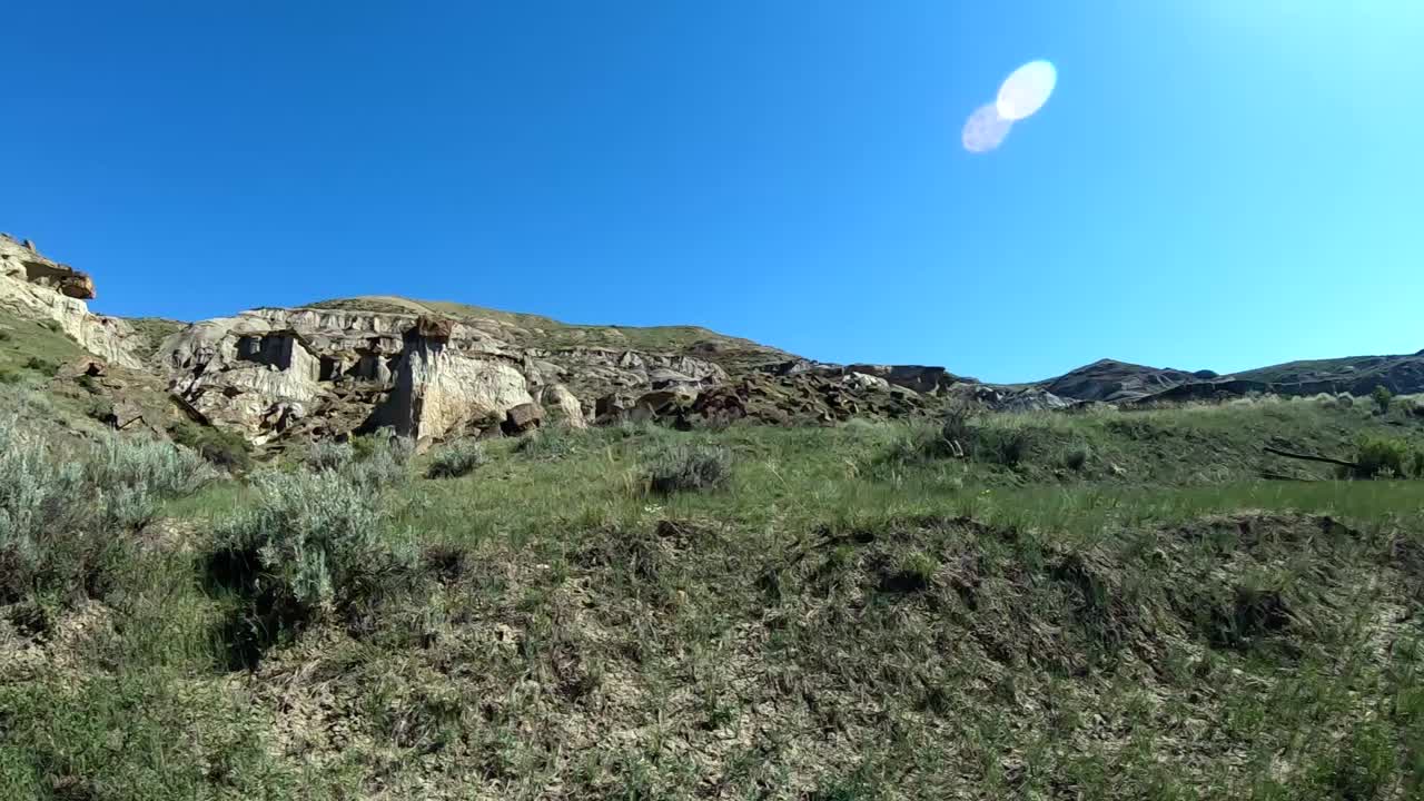 Rocks, grass,  and a mountain at Sandy Point Alberta Canada on a sunny day.