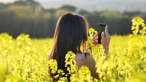 delighted woman taking pictures of blossoming field