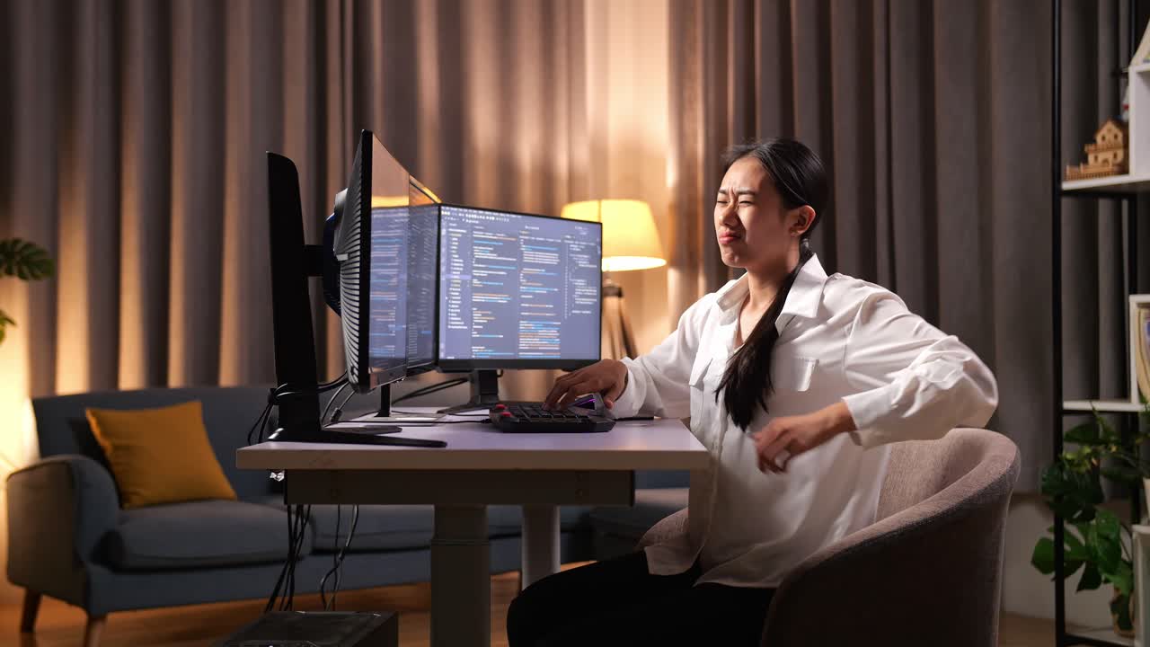 아시아 여성 프로그래머가 소프트웨어 엔지니어를 만들면서 허리 통증을 겪고 있습니다. 집에서 데스크 컴퓨터에서 앱, 프로그램, 비디오 게임을 개발하고 있습니다. 코딩 언어를 가진 터미널.
