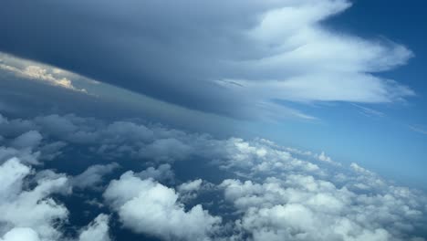 breathtaking view from an airplane cabin while flying just bellow a huge cumulonimbus storm cloud during a left turn to aviod bad weather ahead