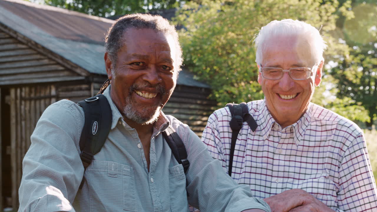 Portrait Of Two Male Senior Friends Hiking In Countryside