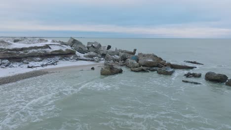 aerial view of abandoned seaside fortification buildings at karosta northern forts on the beach of baltic sea , overcast winter day, wide drone shot moving forward low