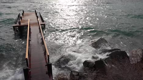 huge waves crash into a pier and shore on the banks of lake tahoe during a big winter storm