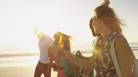 amigos adultos jóvenes caminando por una playa al atardecer 4k