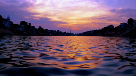 vibrant sunset reflections on rippling water with distant cityscape