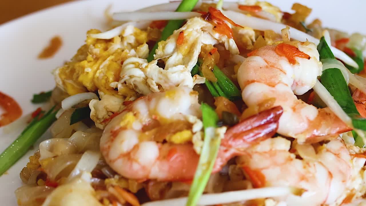 A vibrant dish featuring shrimp, scrambled eggs, and fresh vegetables on a white plate.