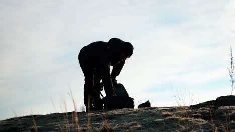 person on rocky hill on bright day remove drone from transportation backpack