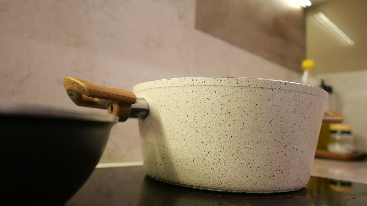 Cooking on a stovetop with a white pot and a black pan
