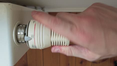 disparo estático de arriba hacia abajo de una mano masculina girando la válvula del radiador termostático a cero