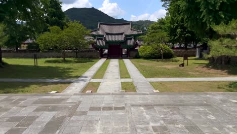 toma inclinada de un hermoso y antiguo templo coreano rodeado de naturaleza verde con árboles y montañas durante la luz del sol