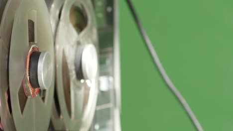 tape recorder playing magnetic deck, closeup side view, green screen background