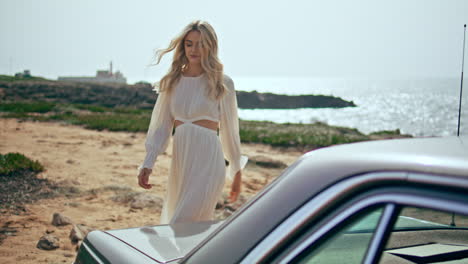 woman walking retro car at sunny sea coast. girl traveler relaxing on seashore.