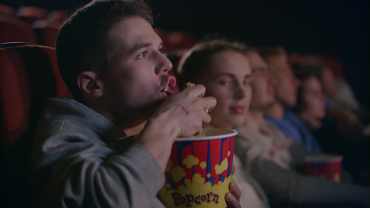 uomo maleducato che mangia popcorn al cinema. maniere maleducate al cinema