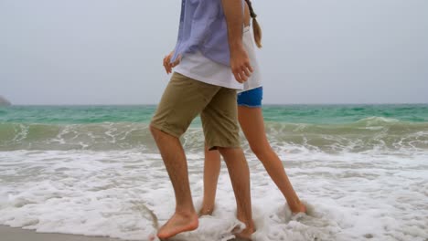 Low-section-of-couple-walking-with-hand-in-hand-on-the-beach-4k