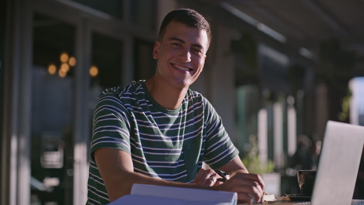 Man smiling with laptop at cafe