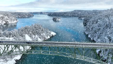 aerial view of cars driving across deception pass in the snow