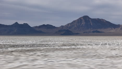 drone shot of bonneville salt flats in utah usa on dry season, barren soil and mountain hills