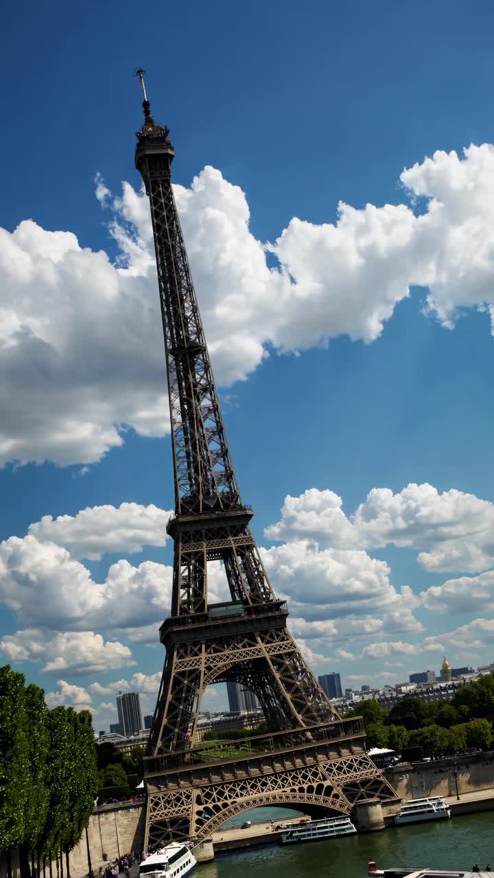 Dynamic low-angle shot of the Eiffel Tower against a backdrop of fluffy clouds