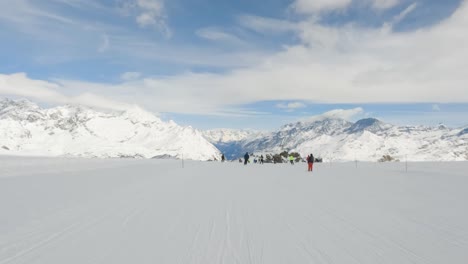 First-person-view-of-skier-ski-on-a-slope-in-swiss-alps-with-mountain-range-background