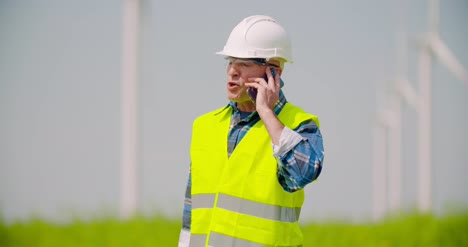 Wütender-Ingenieur,-Der-Am-Handy-Gegen-Windmühlenfarm-Spricht