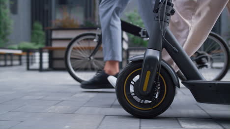 managers legs walking downtown street. front bicycle scooter wheels close up.