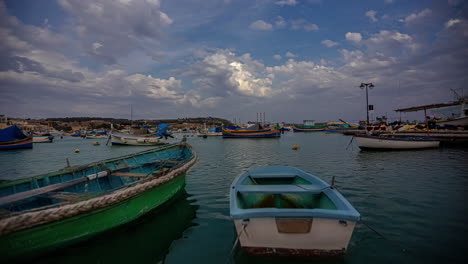 Barcos-Anclados-En-El-Puerto-De-Marsaxlokk,-Malta,-Con-Un-Increíble-Lapso-De-Tiempo-De-Nubes